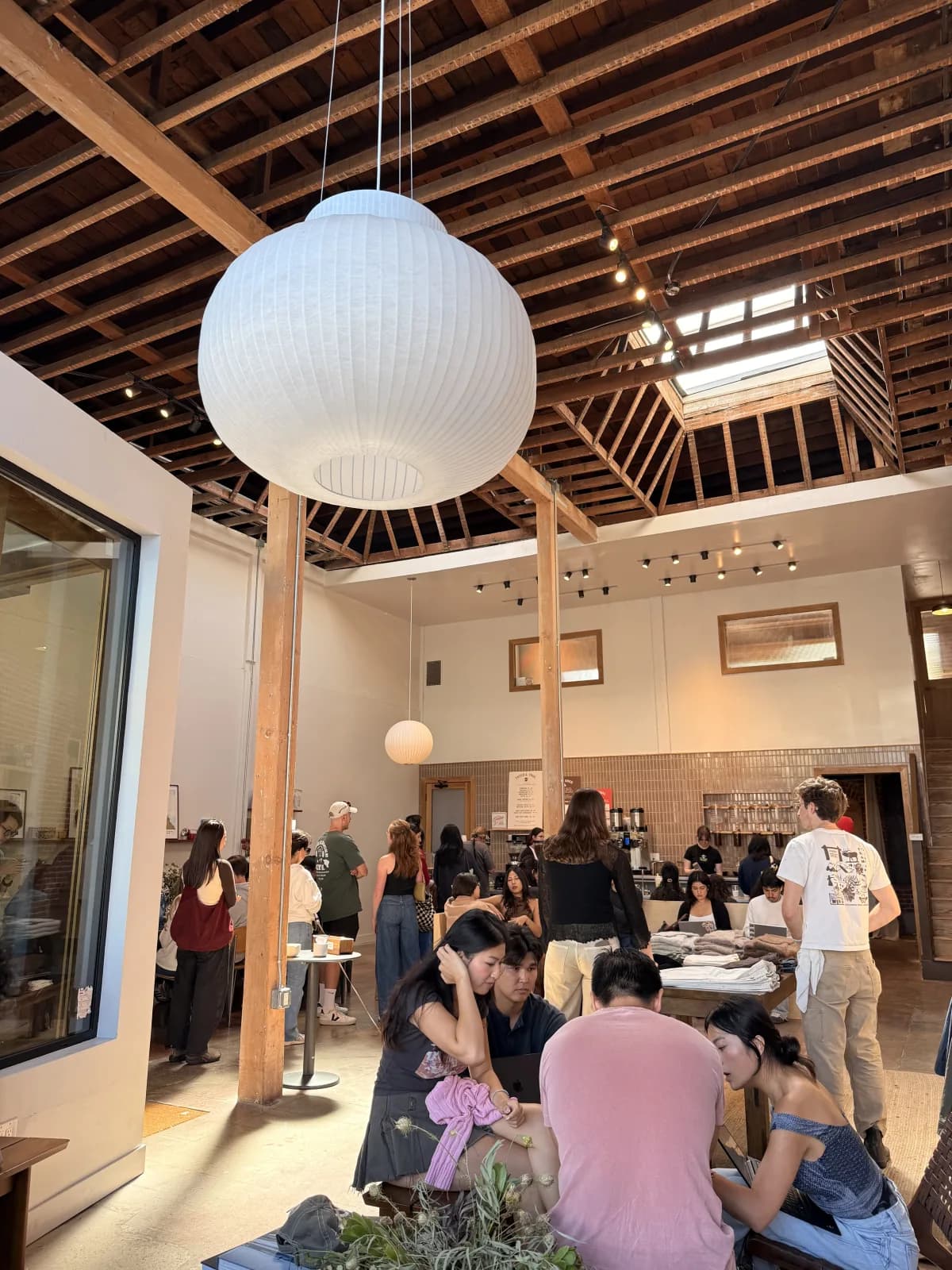 Sunlit interior of Double Black Cafe with exposed wood rafters and a large globe pendant